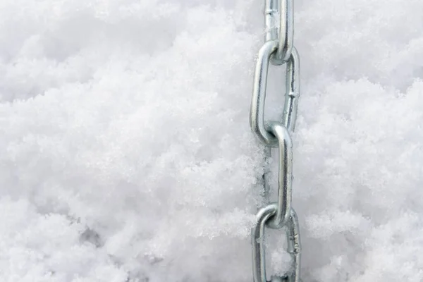 A metal chain lies on the snow in winter