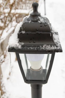Kışın bahçede açık hava siyah feneri.