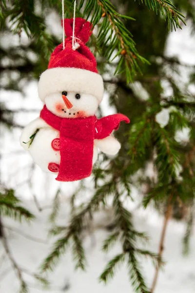 Brinquedo boneco de neve pendurado em uma árvore coberta de neve — Fotografia de Stock