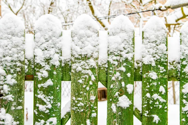 Green fence in snow in winter Stock Photo