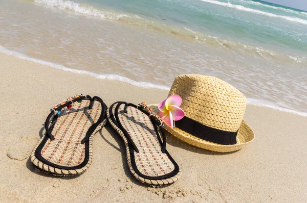 Strandpantoffeln mit Hut am Strand — Stockfoto