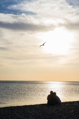 Sahilde gün batımında severler