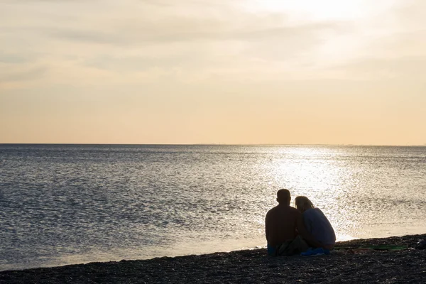 Любовники на закате на пляже — стоковое фото