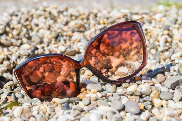 Sluneční brýle na pláži malé oblázky — Stock fotografie