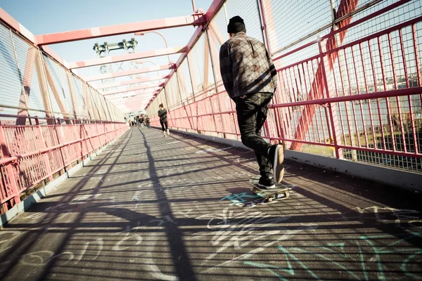 Skateboarder cruise op brug — Stockfoto