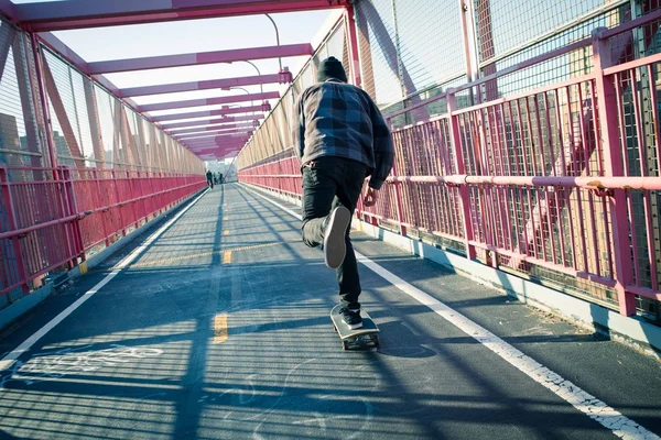 Skateboarder cruise op brug — Stockfoto