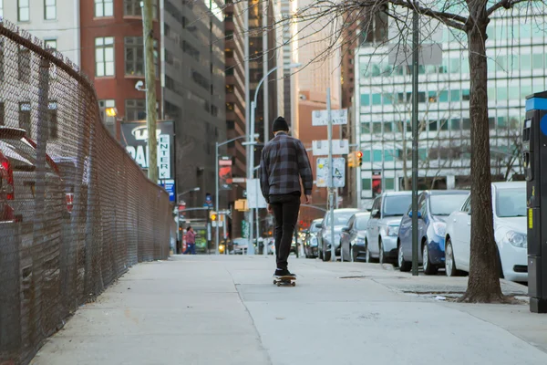 Full back figure of a skateboarder cruising down city — Stock Photo, Image