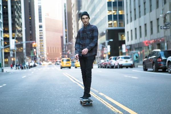 Young skateboarder cruising donw the city street before sunset Stock Photo