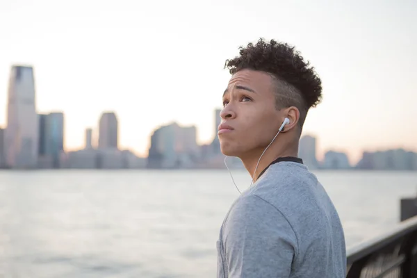 Young hispanic boy listening to music while facing the river — Stock Photo, Image