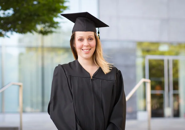 Porträtt av kvinnliga collegestudent i examen mössa och klänning på — Stockfoto