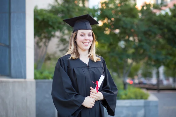 Ritratto di studentessa universitaria in berretto di laurea e abito ho — Foto Stock