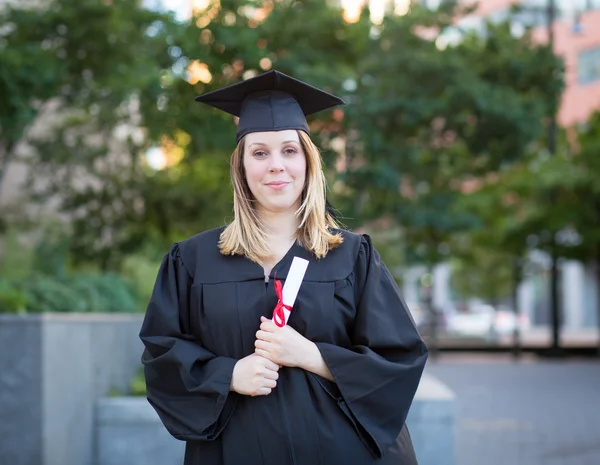 Ritratto di studentessa universitaria in berretto di laurea e abito ho — Foto Stock