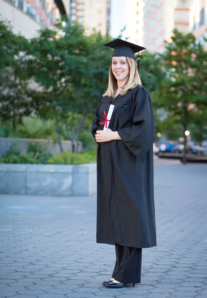 Porträtt av kvinnliga collegestudent i examen mössa och klänning ho — Stockfoto