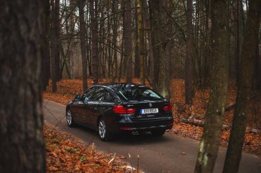 Kyiv, Ukrayna - Kasım 2019. BMW 3 serisi GT sonbahar orman yolunda siyah renkli.