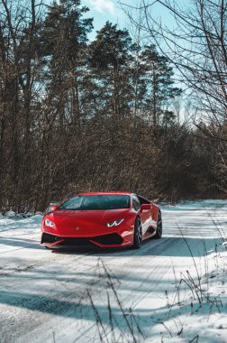 Kyiv, Ukrayna - Şubat 2020. Kızıl Lamborghini Huracan karlı ormanda.
