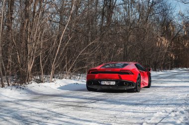 Kyiv, Ukrayna - Şubat 2020. Kızıl İtalyan süper arabası Lamborghini Huracan karlı ormanda.