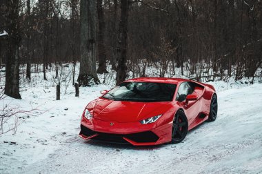 Kyiv, Ukrayna - Şubat 2020. Kızıl İtalyan süper arabası Lamborghini Huracan karlı ormanda.
