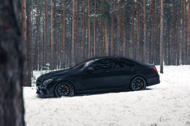 Kherson, Ukrayna - Şubat 2021. Güçlü Mercedes-AMG E63 S Brabus Kışın karlı ormanda mat siyah renkte.
