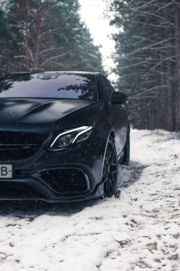Kherson, Ukrayna - Şubat 2021. Güçlü Mercedes-AMG E63 S Brabus Kışın karlı ormanda mat siyah renkte.