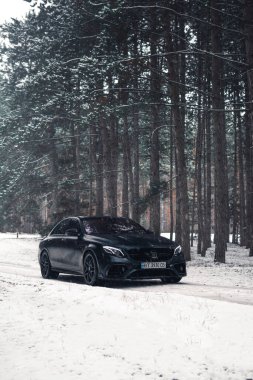 Kherson, Ukrayna - Şubat 2021. Güçlü Mercedes-AMG E63 S Brabus Kışın karlı ormanda mat siyah renkte.