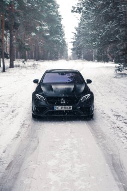 Kherson, Ukrayna - Şubat 2021. Güçlü Mercedes-AMG E63 S Brabus Kışın karlı ormanda mat siyah renkte.