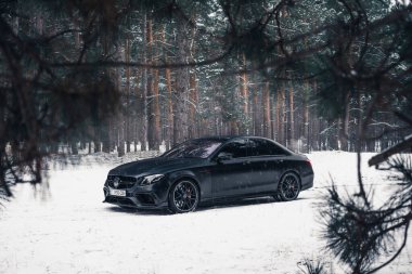 Kherson, Ukrayna - Şubat 2021. Güçlü Mercedes-AMG E63 S Brabus Kışın karlı ormanda mat siyah renkte.