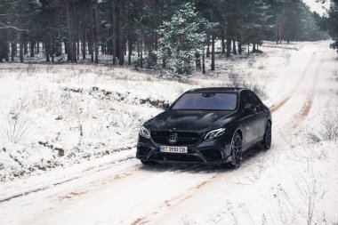Kherson, Ukrayna - Şubat 2021. Güçlü Mercedes-AMG E63 S Brabus Kışın karlı ormanda mat siyah renkte.