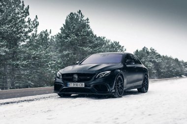 Kherson, Ukrayna - Şubat 2021. Güçlü Mercedes-AMG E63 S Brabus. Karlı ormanda, boş yolda mat siyah bir renk..