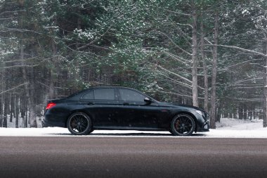 Kherson, Ukrayna - Şubat 2021. Güçlü Mercedes-AMG E63 S Brabus. Karlı ormanda, boş yolda mat siyah bir renk..