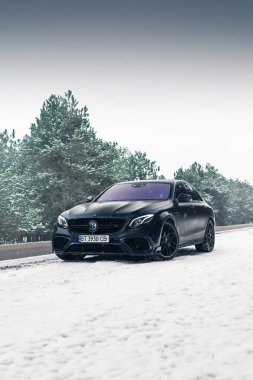 Kherson, Ukrayna - Şubat 2021. Güçlü Mercedes-AMG E63 S Brabus. Karlı ormanda, boş yolda mat siyah bir renk..