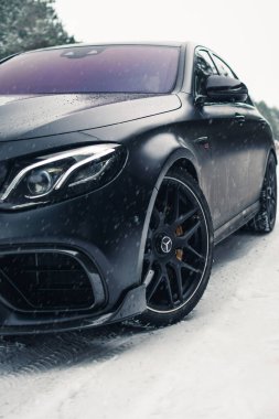 Kherson, Ukrayna - Şubat 2021. Güçlü Mercedes-AMG E63 S Brabus. Karlı ormanda, boş yolda mat siyah bir renk..