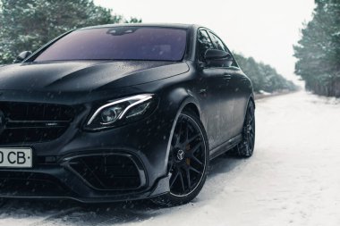 Kherson, Ukrayna - Şubat 2021. Güçlü Mercedes-AMG E63 S Brabus. Karlı ormanda, boş yolda mat siyah bir renk..