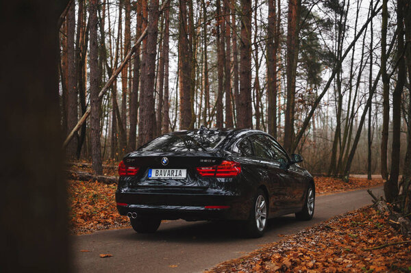Киев, Украина - ноябрь 2019 года. BMW 3-й серии GT в черном цвете на осенней лесной дороге.