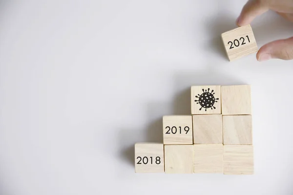 New year 2020 (Covic19) to 2021 with hand putting wood cube in progress bar.