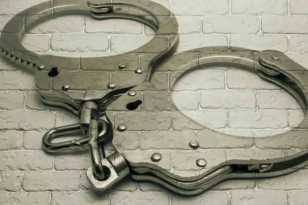 Handcuffs on background of gray brick wall — Stock Photo, Image