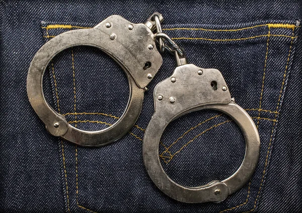 Police steel handcuffs  on jeans — Stock Photo, Image