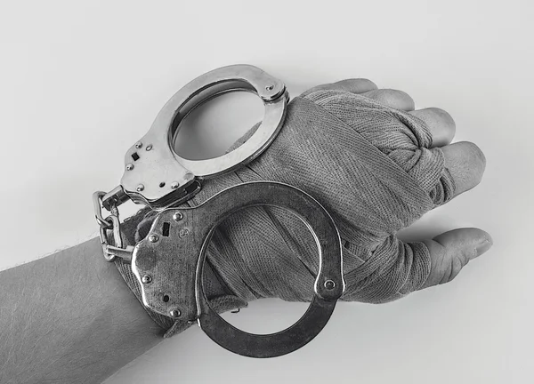 Hand in a boxing bandage with handcuffs — Stock Photo, Image