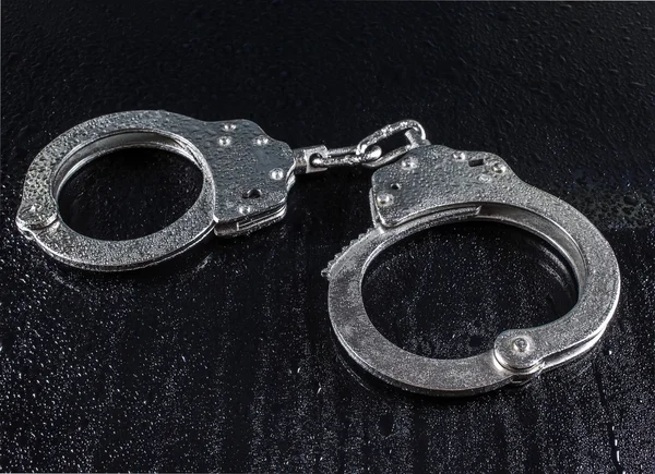 Police handcuffs on a dark background in the drops — Stock Photo, Image