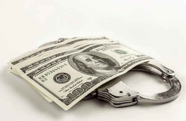 Долари і сталеві наручники на білому тлі — стокове фото