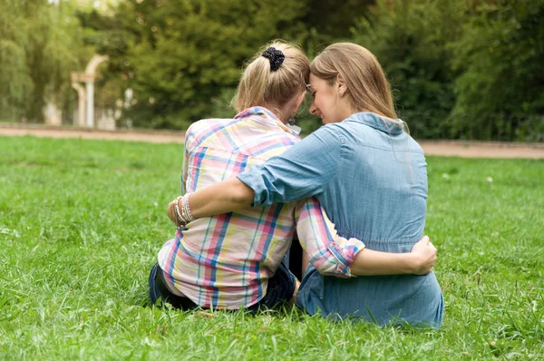 Duas meninas ao ar livre sentado na grama e abraçando uns aos outros — Fotografia de Stock