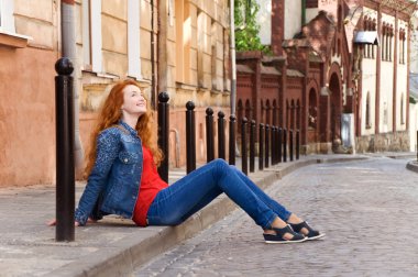 Yalnız kız turistik yol boyunca kaldırıma oturur