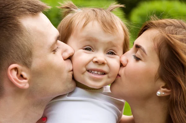 mom and dad kiss cheeks their daughter