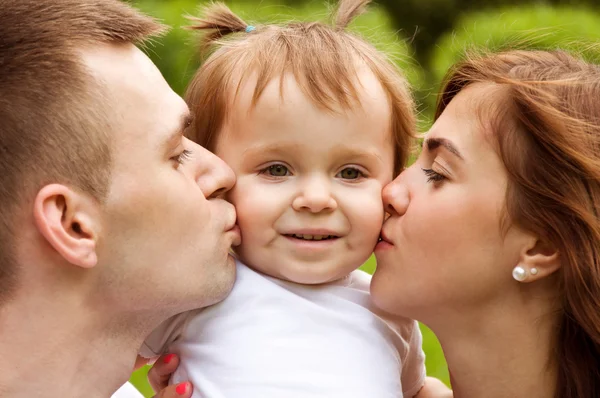 mom and dad kiss cheeks their daughter