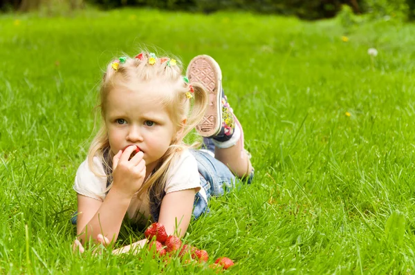 Malá holčička jíst jahody v přírodě — Stock fotografie