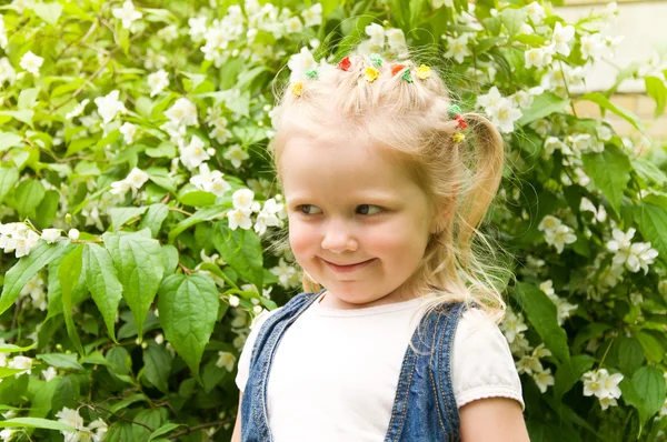 Happy little girl standing with white flowers — Stock Photo, Image