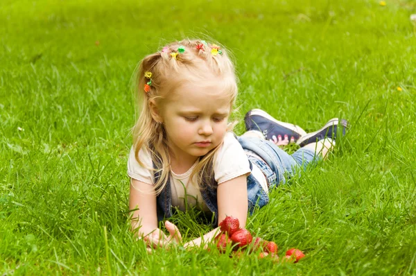 Lilla flickan äta en jordgubbe i naturen — Stockfoto