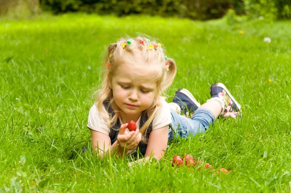 Malá holčička jíst jahody v přírodě — Stock fotografie