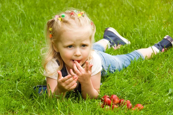 Маленькая девочка ест клубнику на природе — стоковое фото