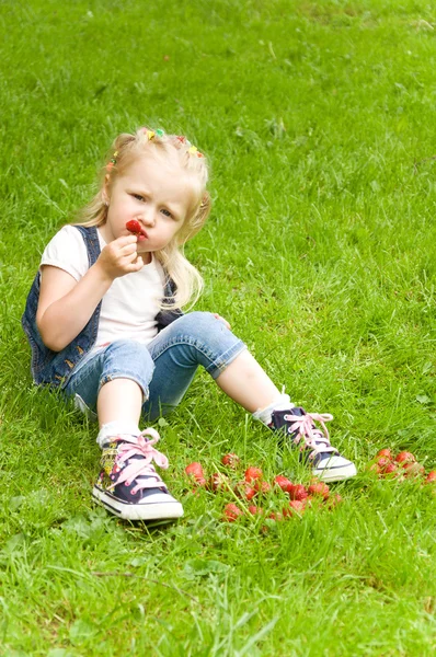 Niña comiendo una fresa en la naturaleza — Foto de Stock