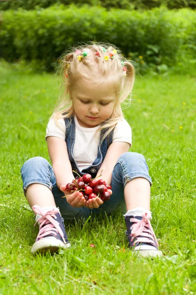 Маленькая девочка ест вишню на природе — стоковое фото